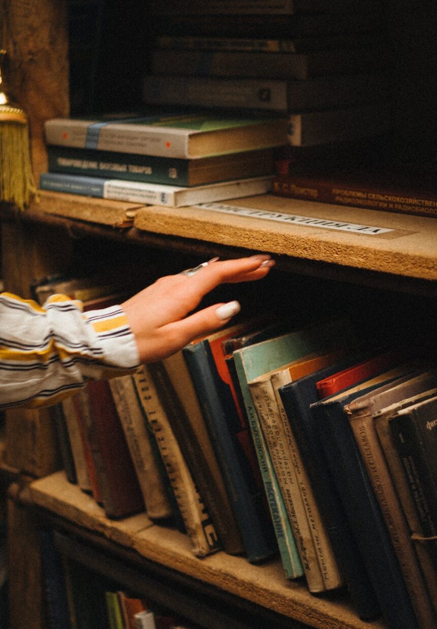 pexels photo 11870983 woman hand over books on shelves
